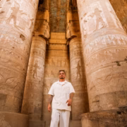 Visitor walking between massive columns at the Temple of Hathor in Dendera Egypt